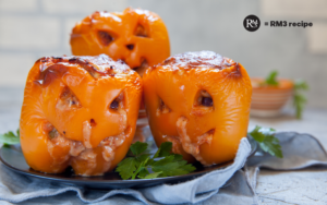 Festive Jack O’ Lantern stuffed orange bell pepper filled with ground turkey, carved with a spooky face in a casserole dish, perfect for Halloween appetizer - RM3®